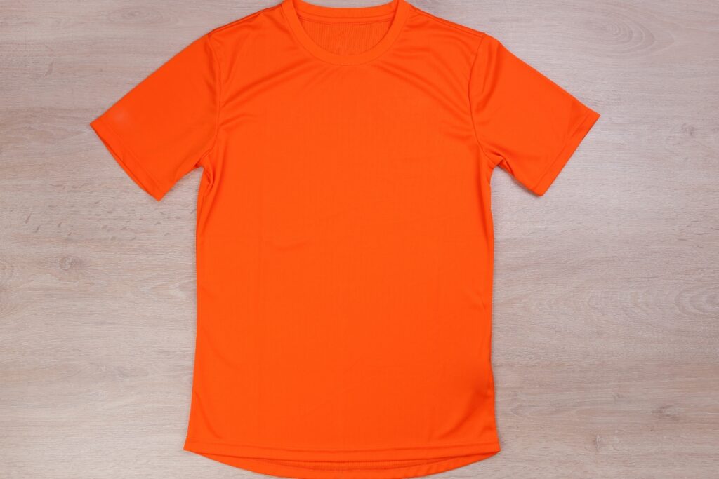 An orange t-shirt for men on a wooden floor.