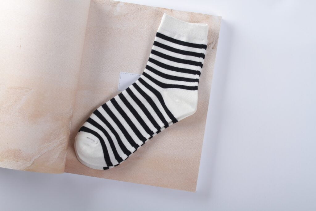 A pair of black and white striped socks on top of a book with golf apparel for men.