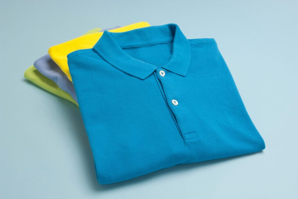 A stack of fall golf attire polo shirts on a blue background.