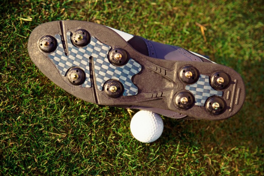 A close up of a shoe with compression golf socks and a golf ball.