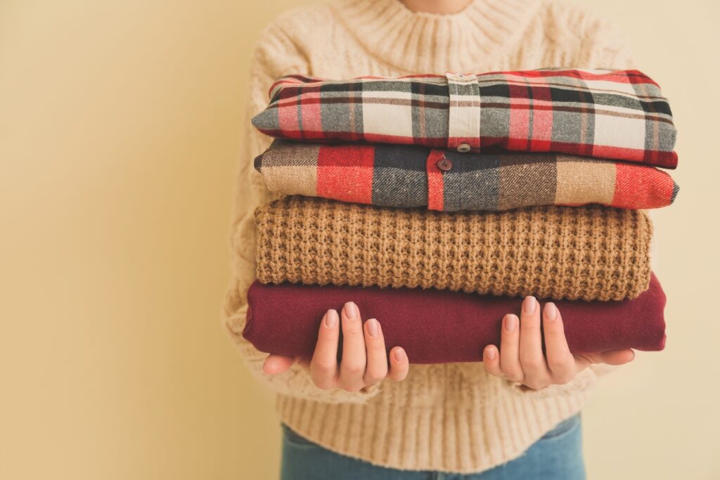 A woman is holding a stack of sweaters, ready for a round of golf in the winter.