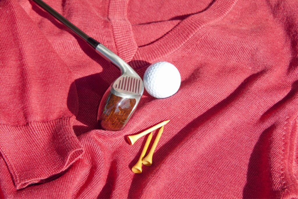 A golf club and a golf ball on a red sweater, showcasing the rich history of golf attire.