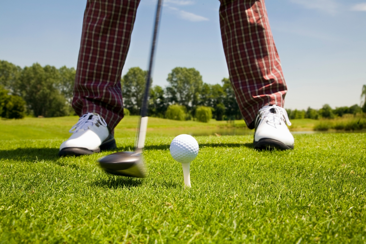 A golfer's feet on the grass next to a golf ball, showcasing the perfect combination of golf and lifestyle apparel.