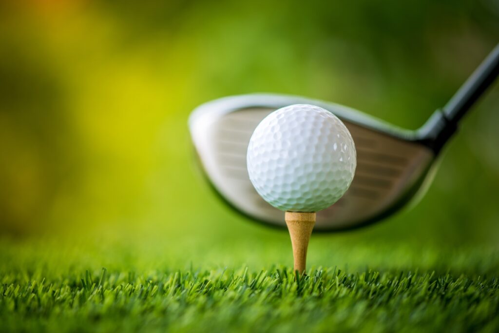 A modern golf ball on a tee with a golf club in the background.