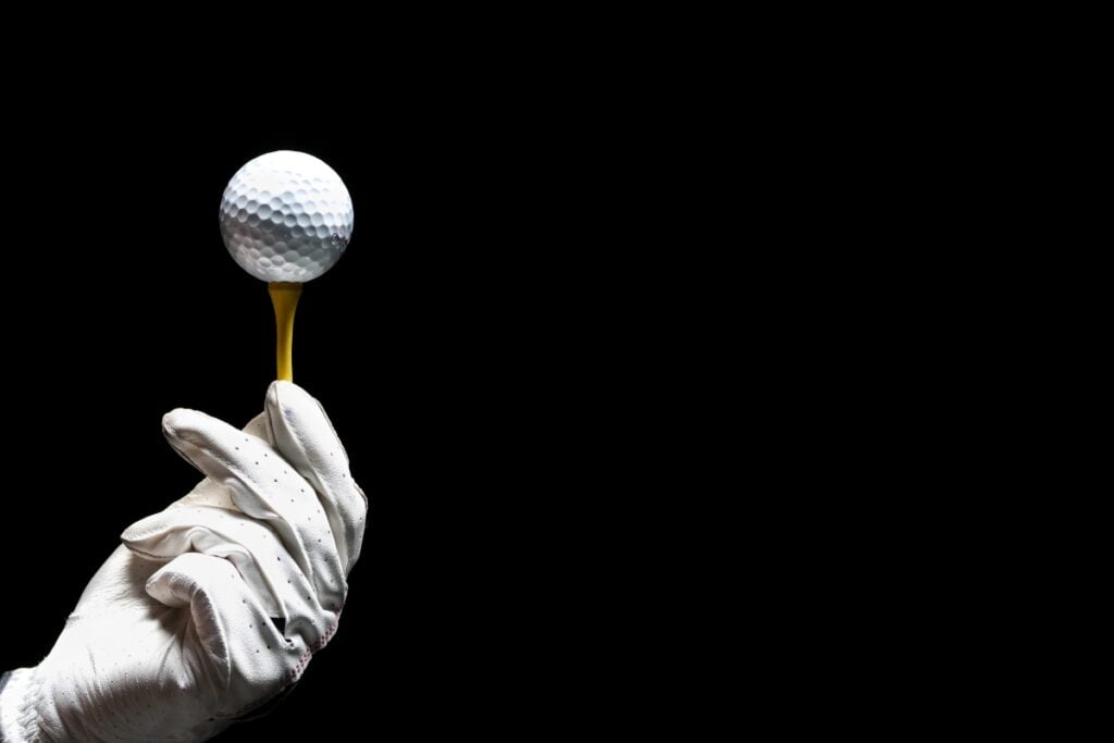 A modern hand gripping a golf ball on a sleek black background.