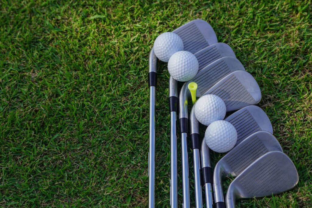 A modern group of golf clubs and balls on the grass.