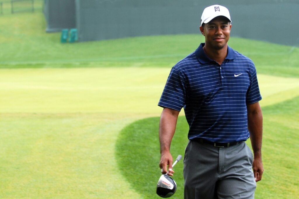 Tiger Woods walking on a golf course in pro golf apparel.