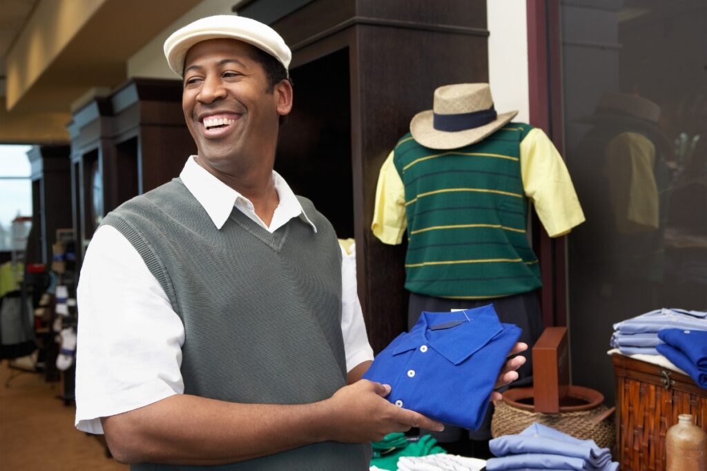 Man smiling while shopping for sustainable golf apparel in a retail store.