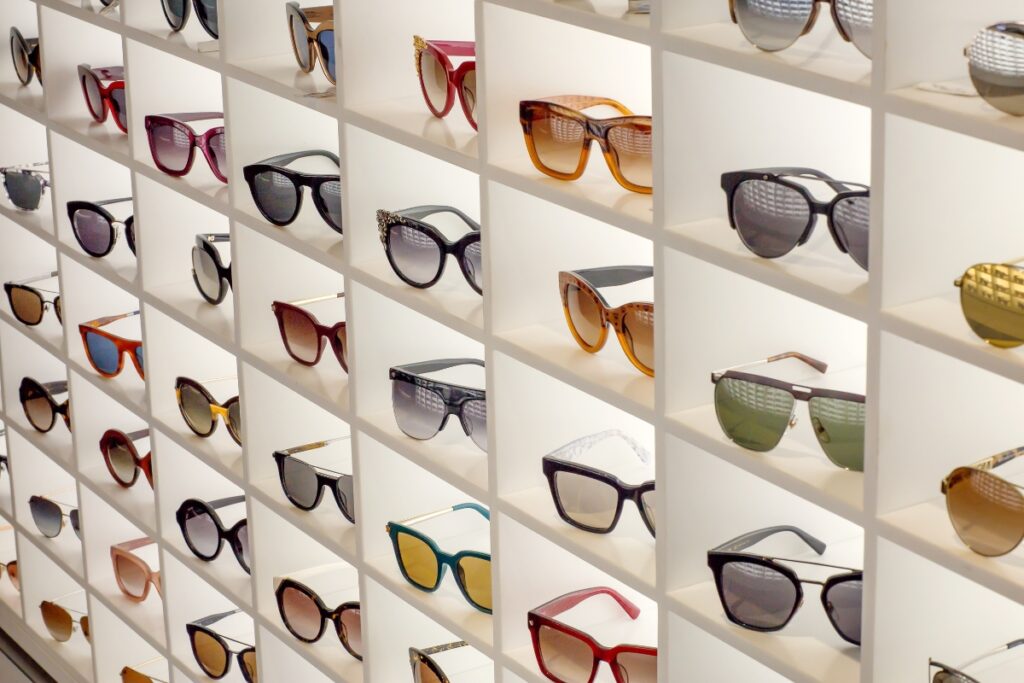 A wall display of various styles of golf sunglasses neatly arranged in individual white compartments.