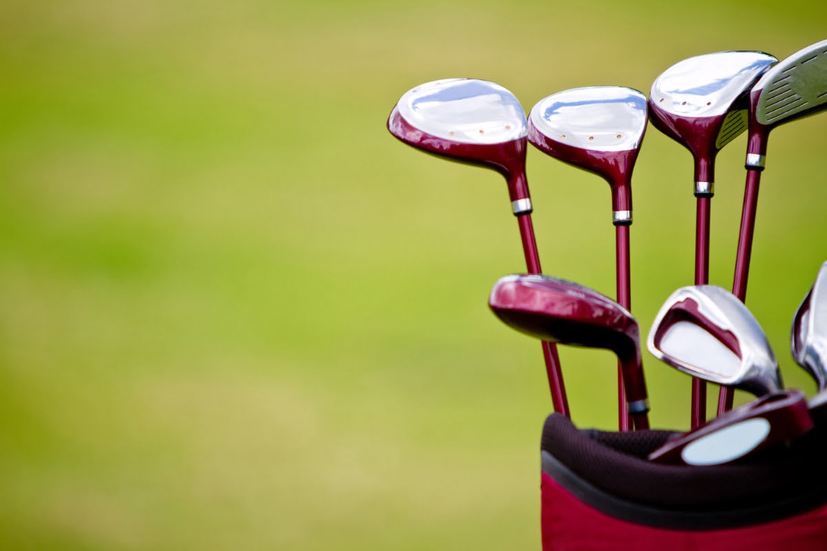 A set of golf clubs with red shafts and silver clubheads in a red golf bag, positioned outdoors with a green grassy background, perfect for your next golf business networking event.