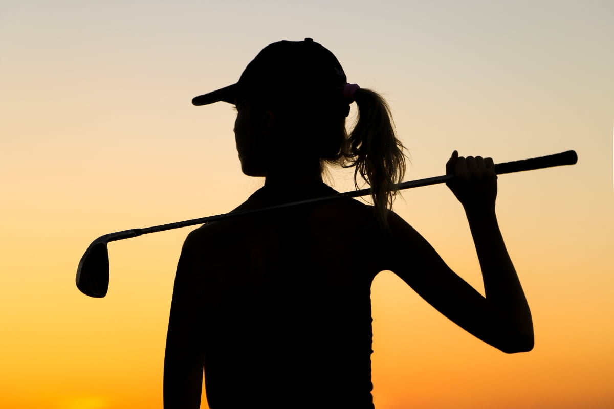 Silhouette of a person wearing a hat, holding a golf club over their shoulder against a sunset background, capturing the essence of golf mindfulness.