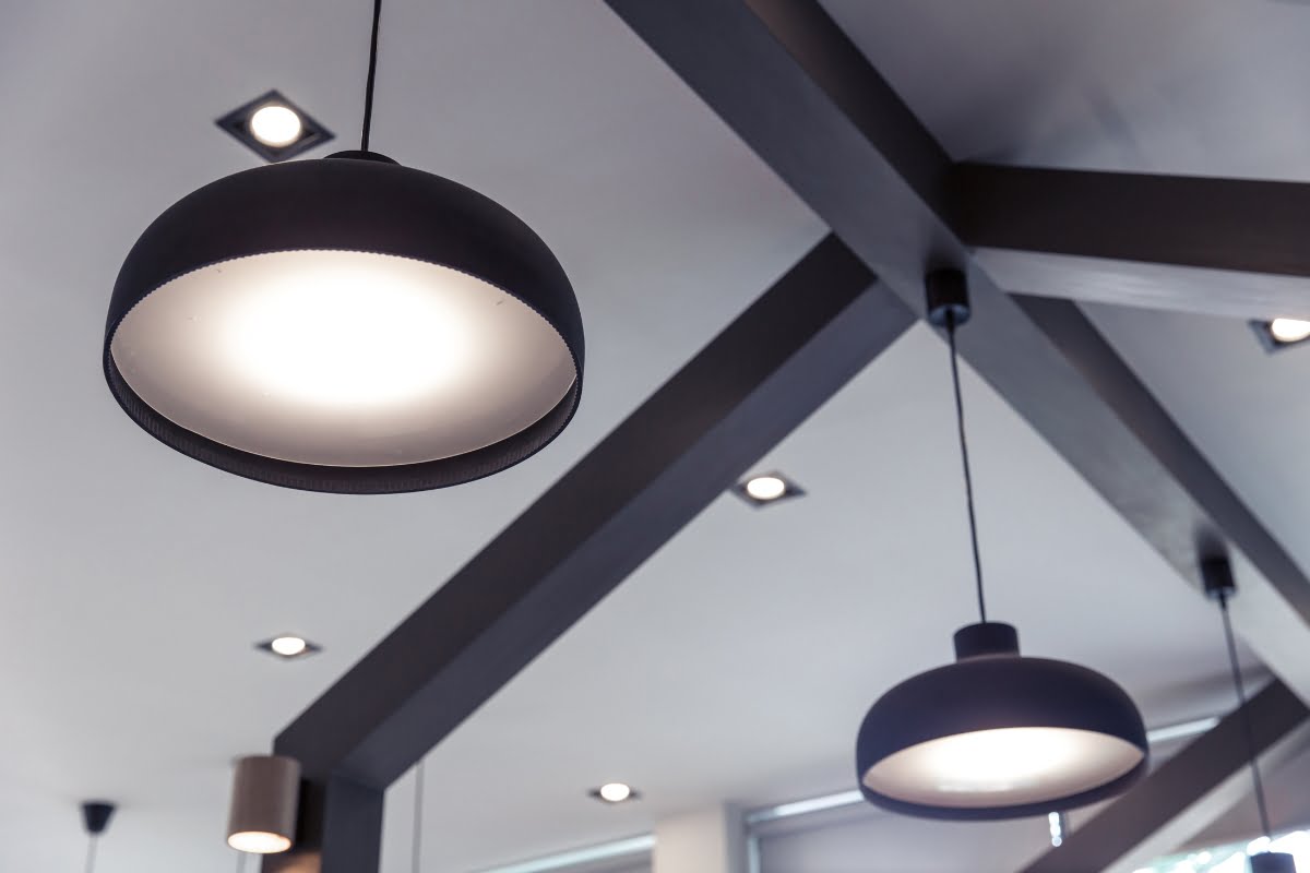 Modern geometric ceiling design with large, round black hanging lights adds a unique touch to golf home decor.