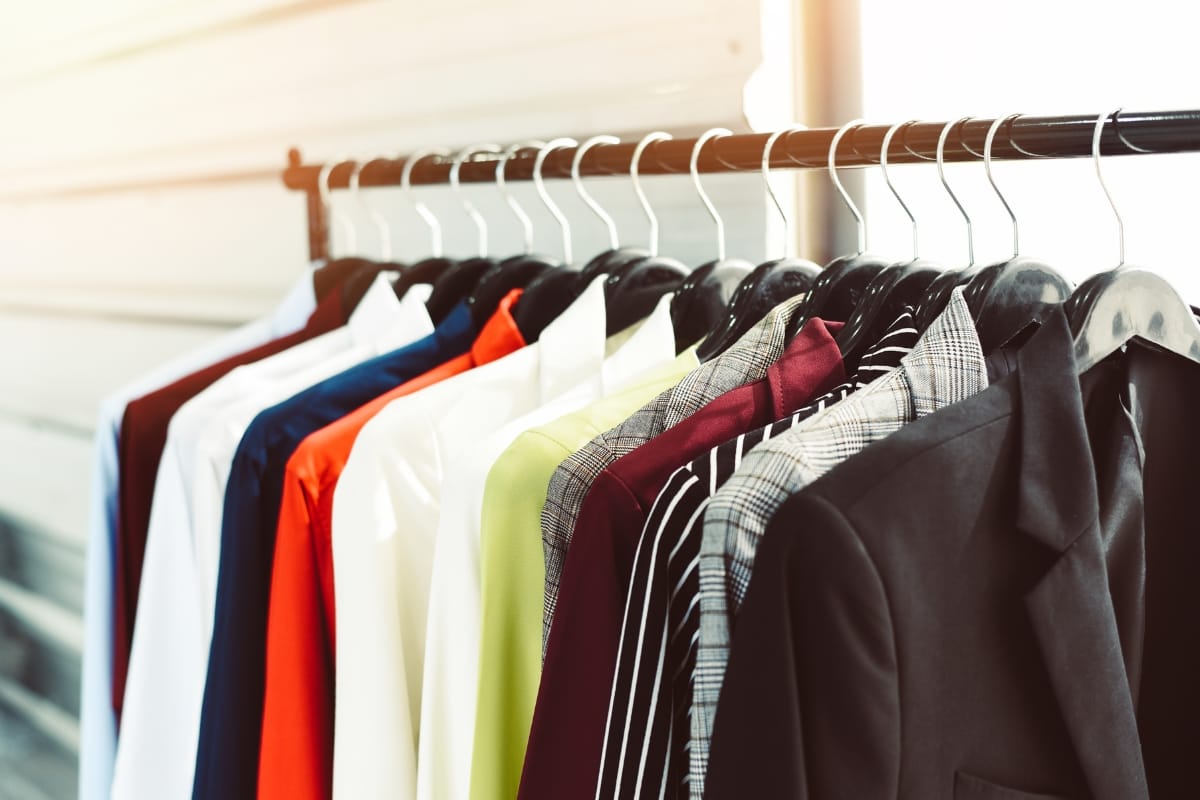 A row of various colored shirts and jackets, including sleek professional golf attire, hangs neatly on a clothing rack.